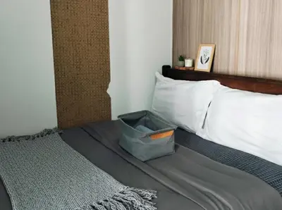 a bed with a basket sitting on top of it at Mall of Asia - Aseana Nice and Cheap Apartment in Manila
