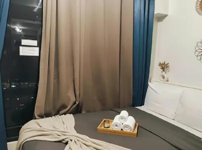 a bed with a tray of towels and a window at Mall of Asia - Aseana - Walking Distance to Mall in Manila