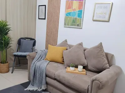 a living room with a brown couch with yellow pillows at Value for Money Mall of Asia - Aseana City Center in Manila
