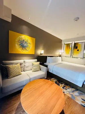 a hotel room with a bed and a couch and a table at Novotel Suites Residences Mandaluyong-Makati by Marj in Manila