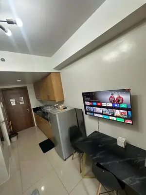a kitchen with a table and a television on the wall at Shell Residences pool view in Manila