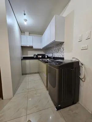 a kitchen with white cabinets and a black stove at Beacon Makati Skyline View in Manila