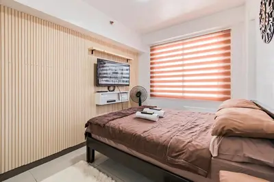 a bedroom with a bed and a flat screen tv at Prime Studio Unit at Robinson Magnolia 5 mins Walk to Mall-Netflix-KTV-WiFi in Manila