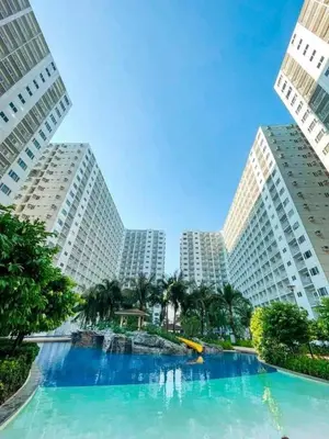 a large swimming pool in the middle of two tall buildings at Cozy room for couple and family near mall of asia in Manila
