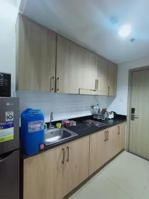 a kitchen with wooden cabinets and a sink at Cozy room for couple and family near mall of asia in Manila