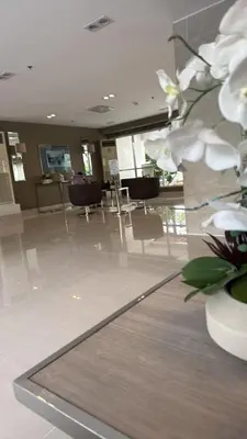 a lobby with chairs and a vase with white flowers at Verlyn Place At Sea Residences Near Moa in Manila