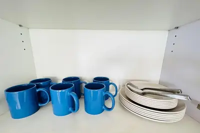 a group of blue cups and plates in a cabinet at Ace Suites by the WaterSpa - Budget Family Room in Manila