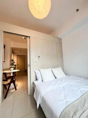 a bedroom with a large white bed and a table at Jazz Residence T2 Rm 405 Homey Muji Inspired Staycation Big Screen Cinema in Manila