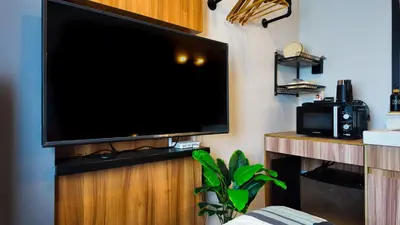 a large flat screen tv on a wooden stand in a room at Studio near SM Megamall 400MBPS Netflix Disney HBO in Manila