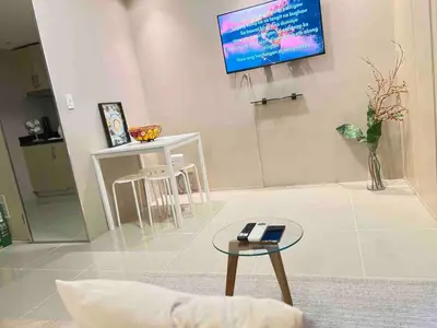 a living room with a table and a tv on the wall at Makati Room 381 1 br deluxe SMJazz T2 residence New in Manila