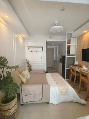 a bedroom with a bed and a table and a kitchen at Cozy Simple Room by Metro Staycation in Manila