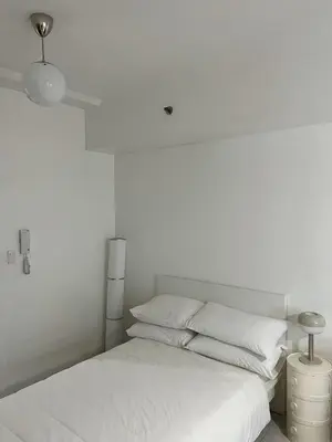 a white bedroom with a bed with white sheets and pillows at The Bauhaus near Eastwood in Manila
