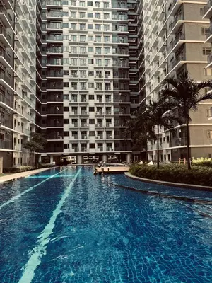 a large swimming pool in front of a large building at Cozy Haven 2 in Manila