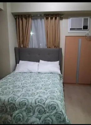 a bedroom with a bed with a green comforter at Rqui Family Room Near Airport in Manila
