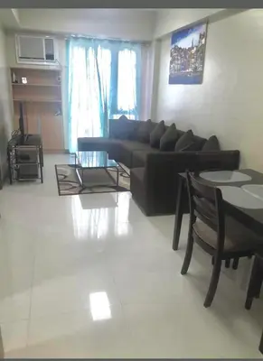 a living room with a black couch and a table at Rqui Family Room Near Airport in Manila