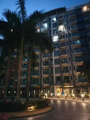 a large building with palm trees in front of it at Rqui Family Room Near Airport in Manila