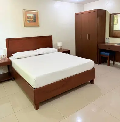 a bedroom with a large bed and a dresser at Joyce Apartelle San Juan in Manila