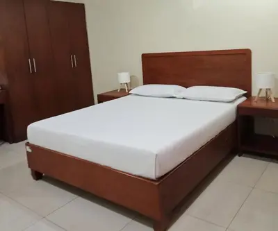 a bed in a bedroom with two nightstands and two tables at Joyce Apartelle San Juan in Manila