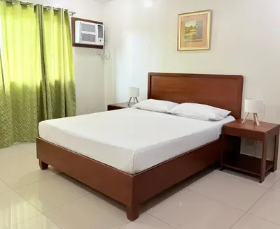 a bedroom with a bed and a green curtain at Joyce Apartelle San Juan in Manila