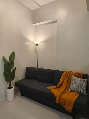 a living room with a black couch with a blanket at The Hmlet Manila, Near Poblacion Makati Nightlife in Manila