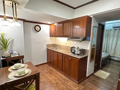 a kitchen with wooden cabinets and a table with plates on it at Isabelle Garden Villas Condominium Paranaque City in Manila