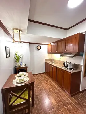 a kitchen with wooden cabinets and a table in it at Isabelle Garden Villas Condominium Paranaque City in Manila