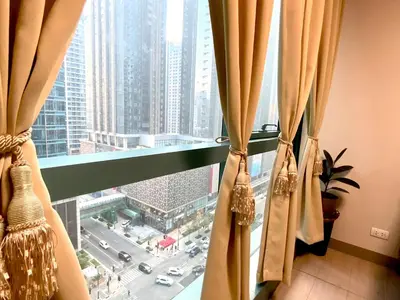a window with curtains with a view of a city at BGC One Uptown in Manila