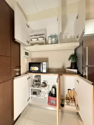 a small kitchen with white cabinets and a microwave at BGC One Uptown in Manila
