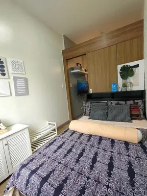 a bedroom with a large bed with a purple comforter at Ohana Residences by SMDC in Manila