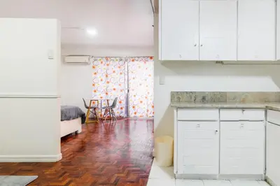a kitchen with white cabinets and a hard wood floor at Stylish Hip studio in the Heart of Poblacion, in Manila