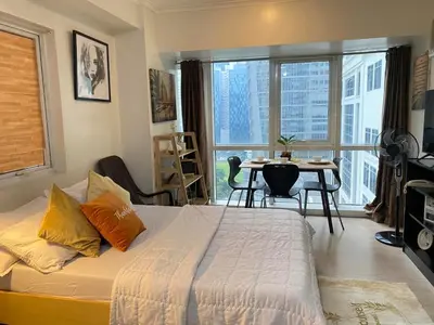 a bedroom with a bed and a table and a window at South of Market Private Residences nr SM Aura BGC in Manila