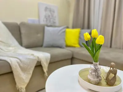a living room with a table with a vase with yellow flowers at The Cozy Cove - 3BR with Netflix, Prime and KTV in Manila