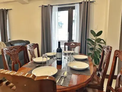 a dining room table with a bottle of wine on it at Hestia Homes near Airport in Manila