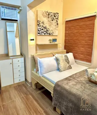 a bedroom with a bed with pillows on it at Staycation in Alabang in Manila