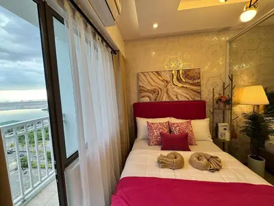 a bedroom with a bed with a large window at Shore Residences Sunset Room facing Manila Bay & City View RM1641 by Prime Stay MOA in Manila