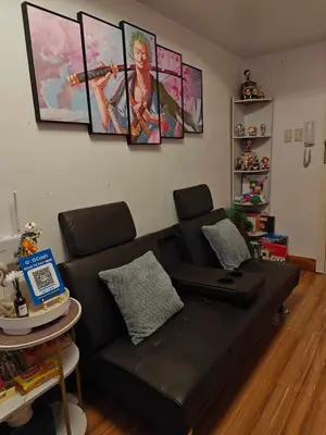 a black couch in a living room with paintings on the wall at Serenity Escapes by Aj in Manila