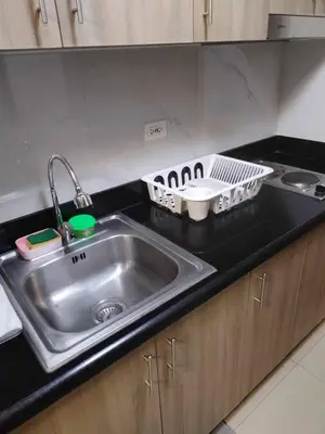 a kitchen counter with a sink and a dish rack at Shore Residence Tower 3 in Manila