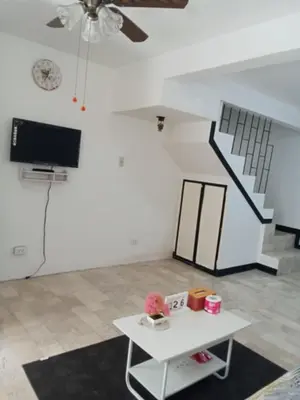 a living room with a white table and a tv at Affordable accommodation near NAIA, MOA and BGC in Manila