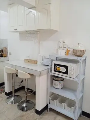 a white kitchen with a counter and a microwave at Affordable accommodation near NAIA, MOA and BGC in Manila