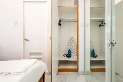 a bedroom with white walls and a glass closet at Forbeswood Heights BGC suite near st Lukes in Manila