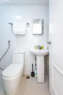 a white bathroom with a toilet and a sink at Forbeswood Heights BGC suite near st Lukes in Manila