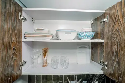 a cupboard with dishes and glasses on it at TahananStays at Makati CBD in Manila