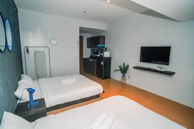 a room with two beds and a flat screen tv at TahananStays at Makati CBD in Manila