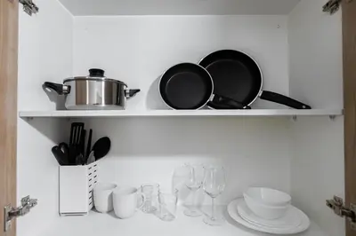 a shelf with pans and plates and wine glasses at SB1054 House in Manila