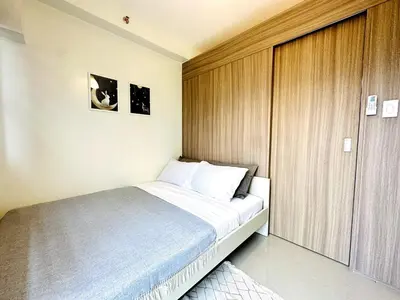 a small bedroom with a bed and a wooden door at OREO1232 House in Manila