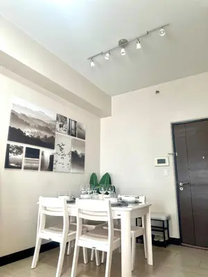 a dining room with a white table and chairs at Cozy 1BR at Greenbelt Hamilton Makati in Manila