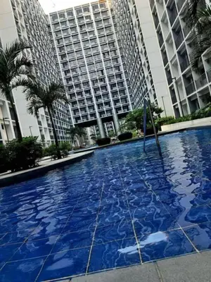 a large swimming pool in front of two tall buildings at Carps Staycation in Manila