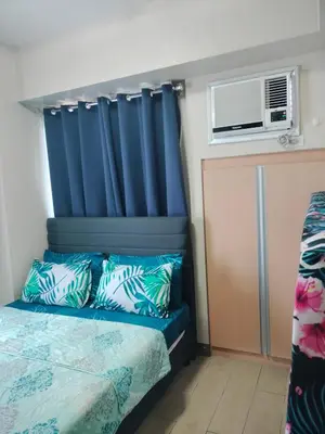 a bedroom with a blue headboard and a bed with pillows at 1 Bedroom Near Airport Pasay City in Manila