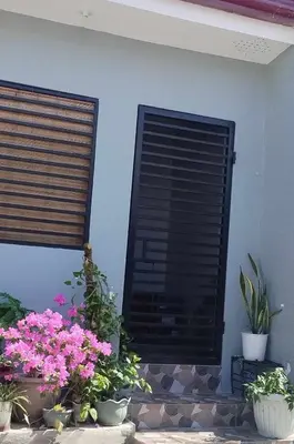 two shutters on a wall with flowers and plants at Rosie's Staycation in Trece Martires, Cavite in Quintana