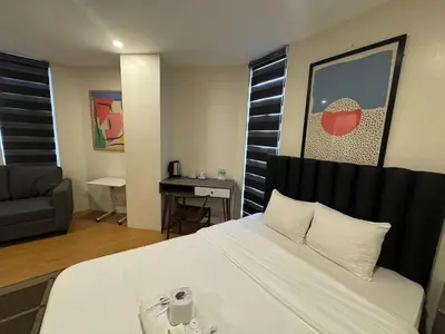 a bedroom with a white bed and a couch at The Circuit Manor Hotel near Ayala Malls Circuit in Manila